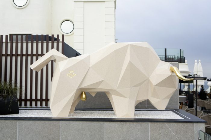 La escultura, con estética origami y cuerpo impermeable de Krion, cuenta con una espectacular cornamenta y testículos en latón brillante pulido