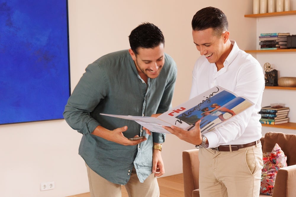 The brothers Roberto and Luis Riu Rodríguez looking at an old RIU Hotels & Resorts magazine