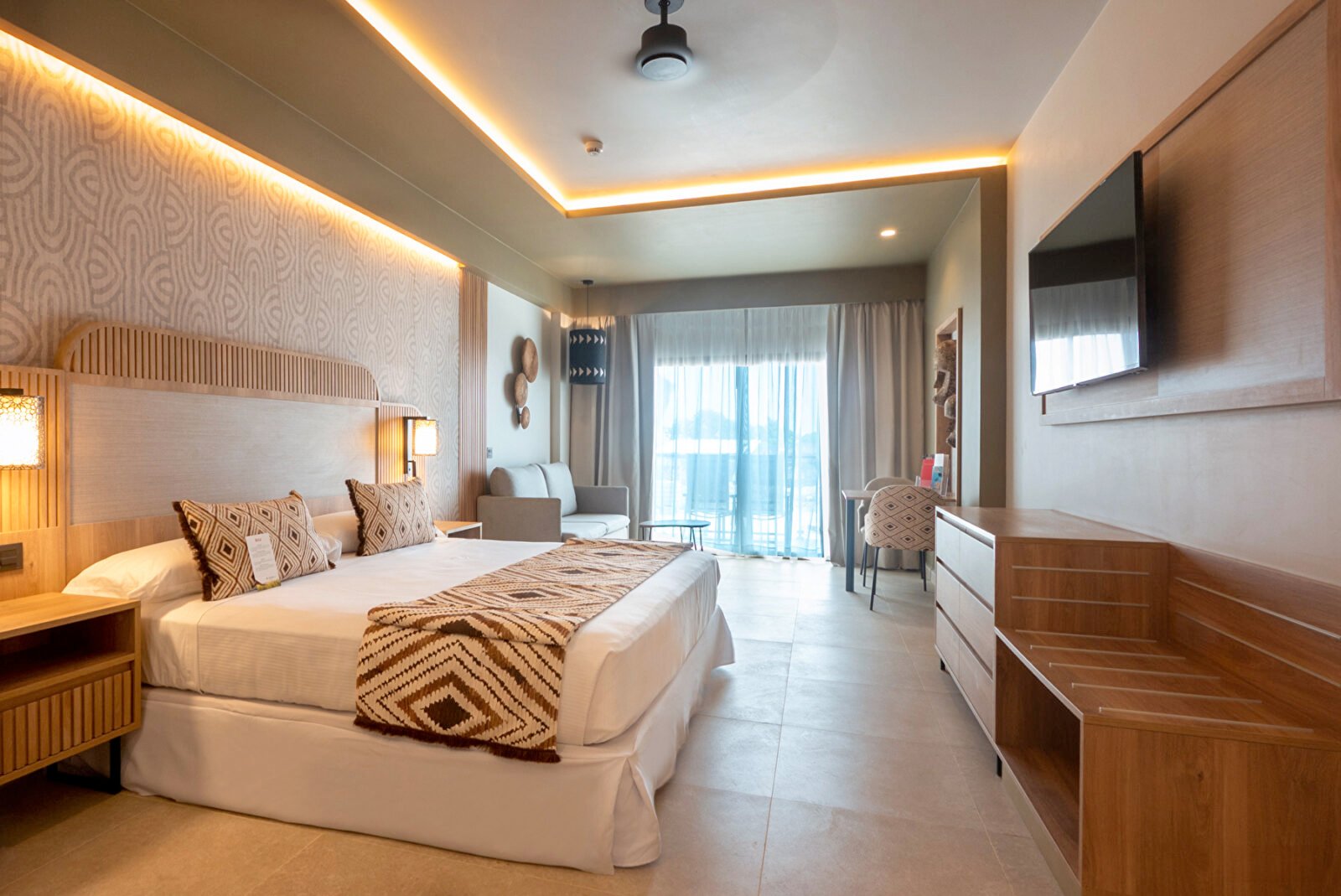 Interior of a Junior Suite at the Hotel Riu Palace Swahili, featuring a modern design with ethnic touches on the bedspread and pillows
