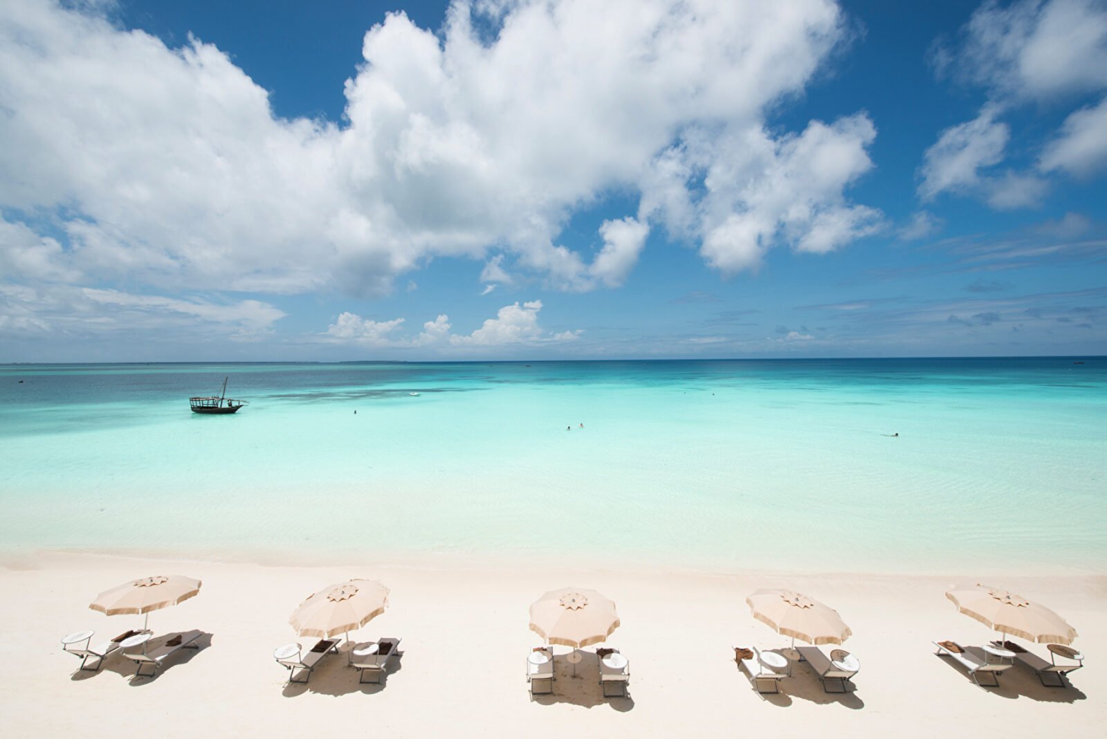 White sandy beach with turquoise waters and parasols in front of the three RIU hotels in Nungwi, Zanzibar