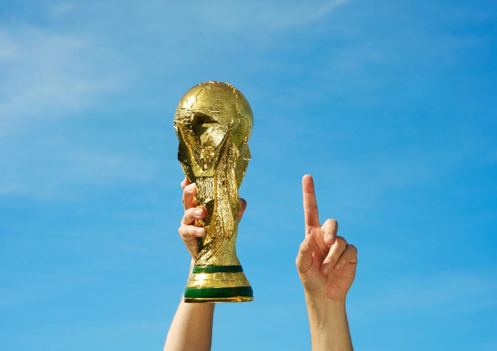 Imagen de una mano sosteniendo el trofeo del mundial de fútbol.