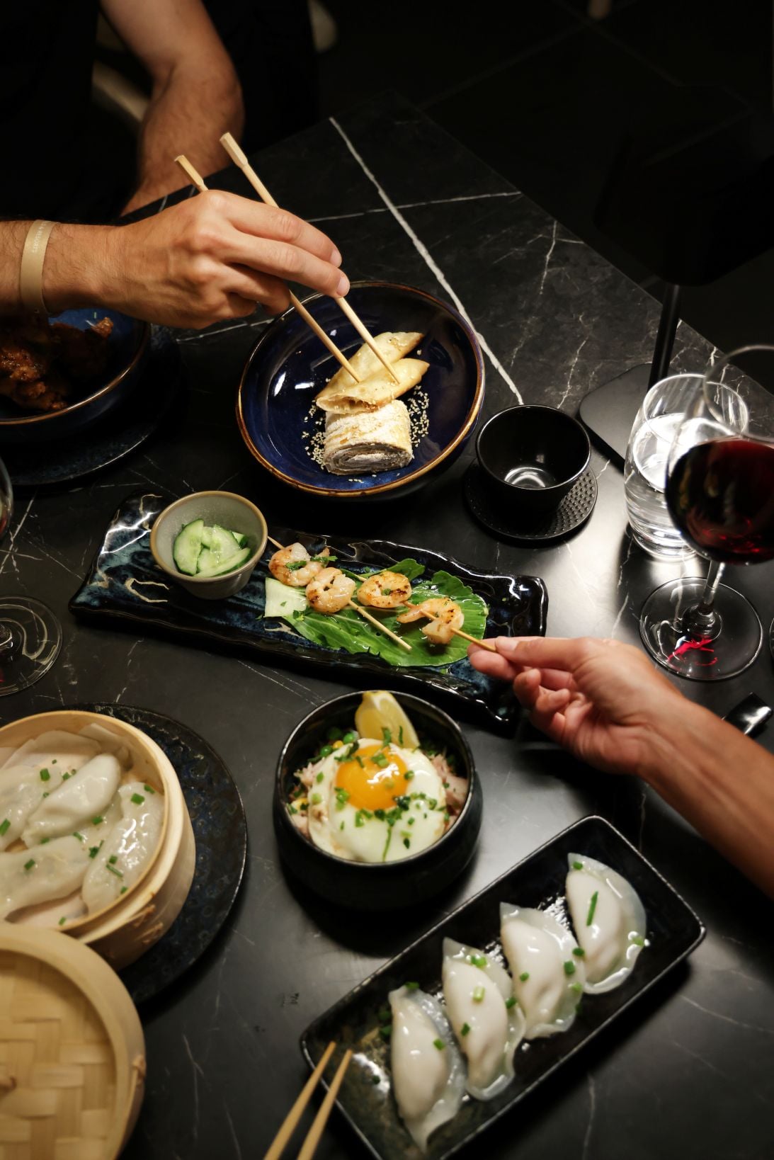 Mesa con platos asiáticos, dim sum en vaporera de bambú y brochetas de langostinos en restaurante de RIU