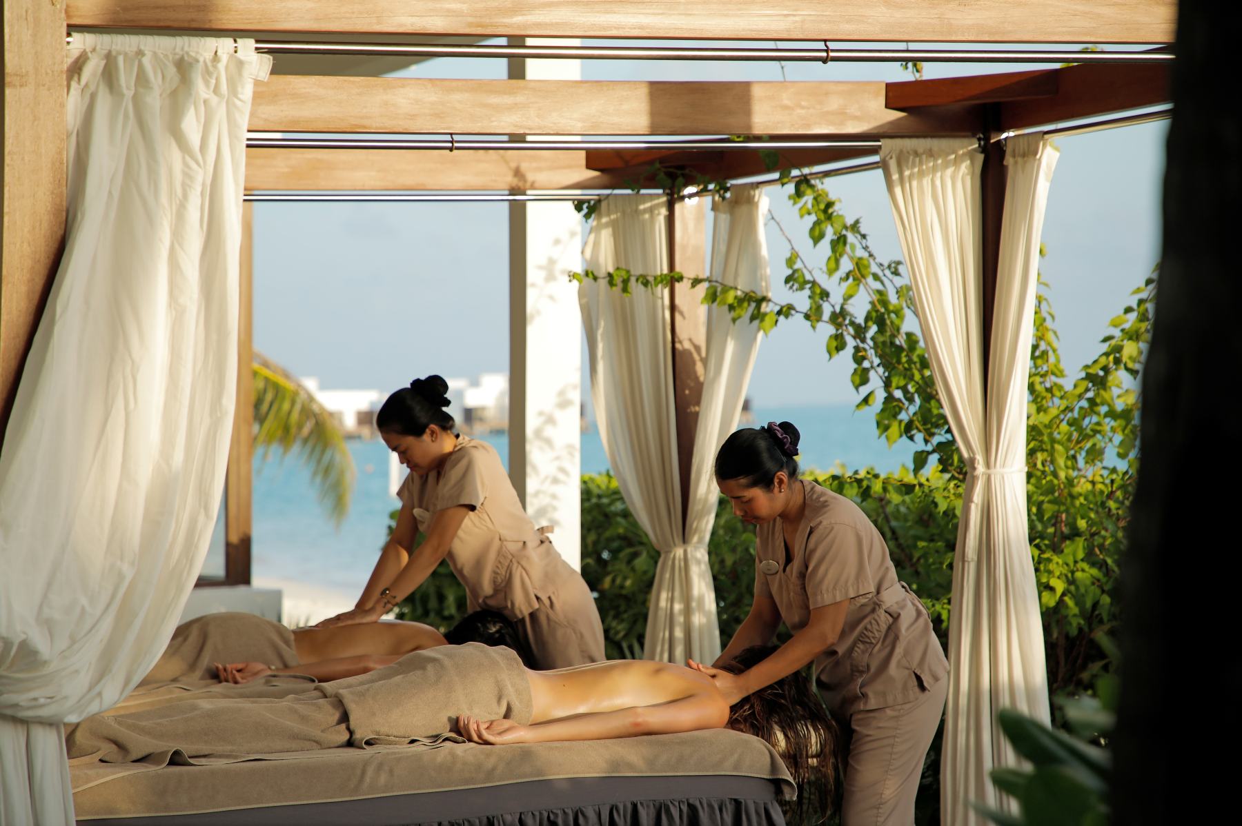 Pareja recibiendo un masaje al aire libre en el spa de un resort tropical RIU.