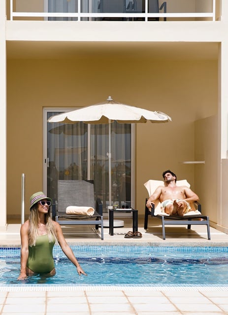 Huéspedes en la terraza de una habitación swim-up con acceso directo a la piscina.