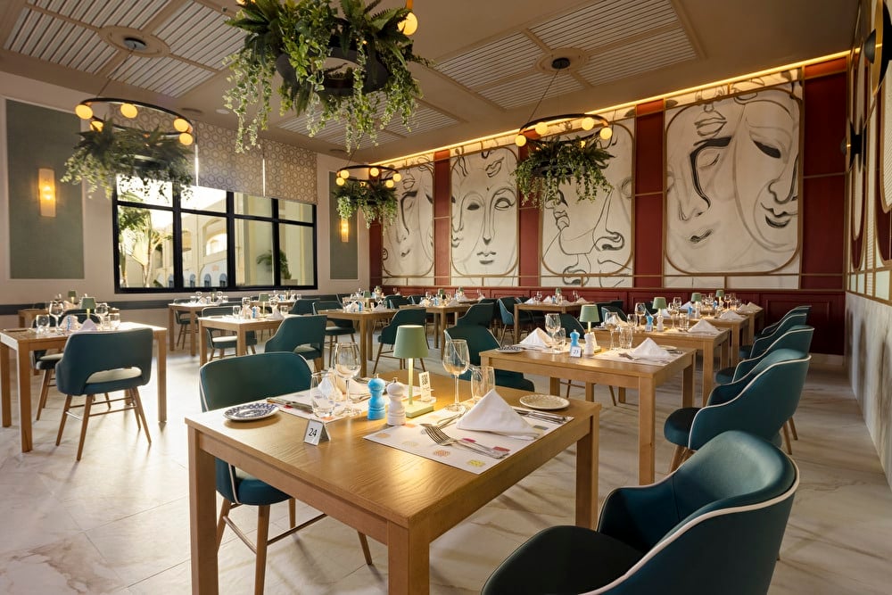 Wide shot of the Italian restaurant at Riu Palace Aruba, featuring abundant natural light and a decor with bright, soft green tones.