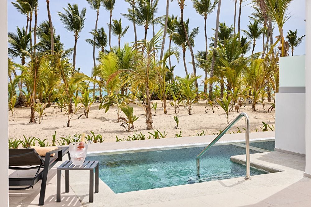 Pequeña piscina privada en la terraza de una suite swim-up frente a la playa, rodeada de palmeras y arena blanca.