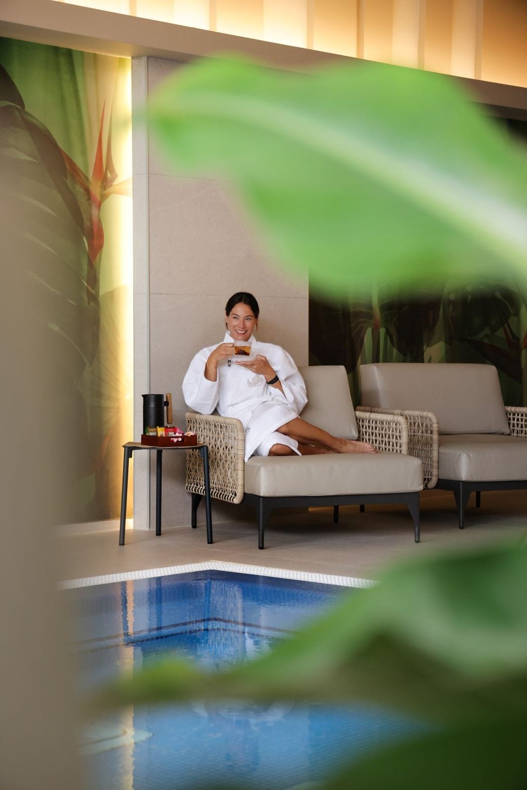 Una mujer se encuentra sentada en una silla dentro de un spa y tomando un café