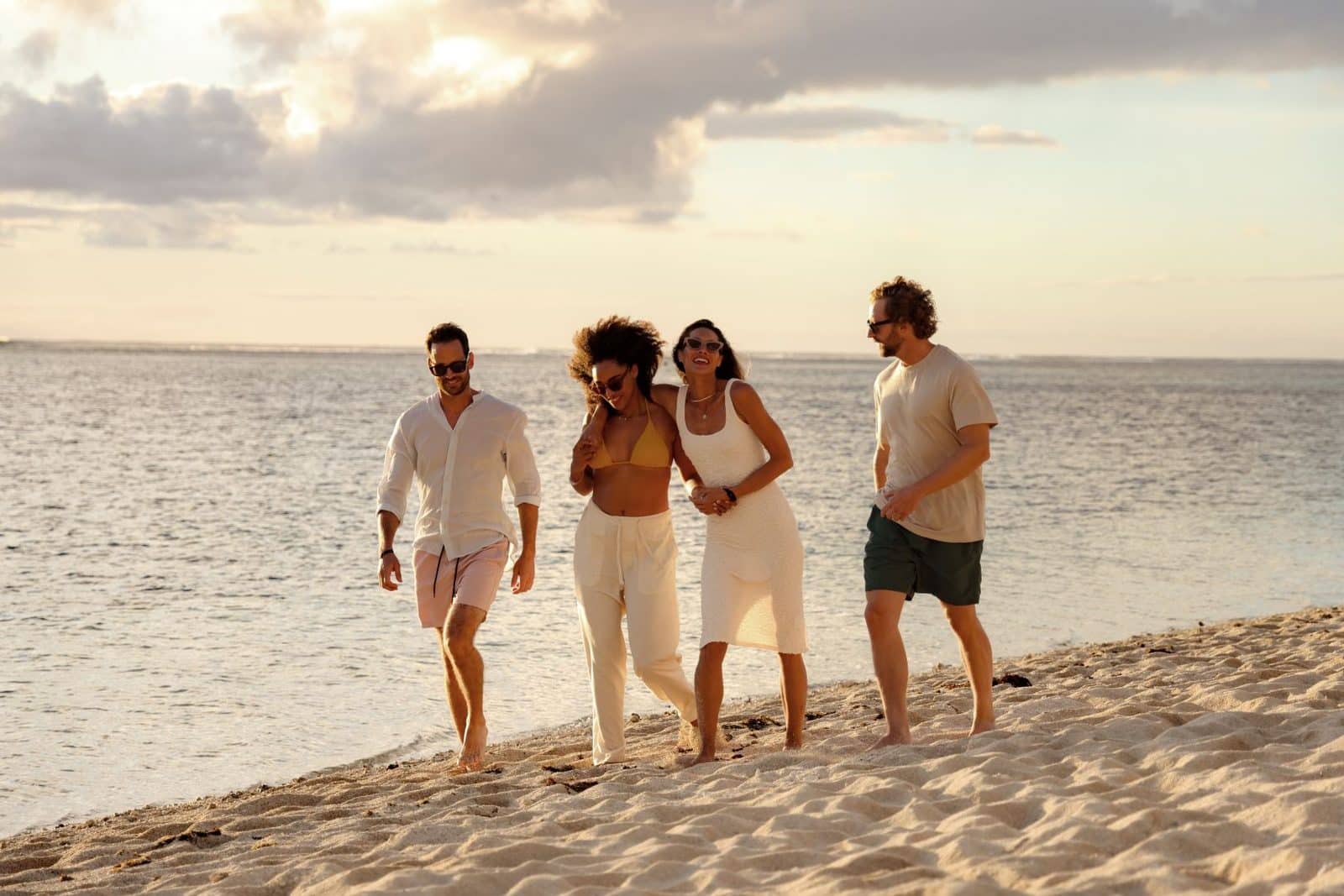 Dos parejas disfrutan de un paseo por la playa al atardecer
