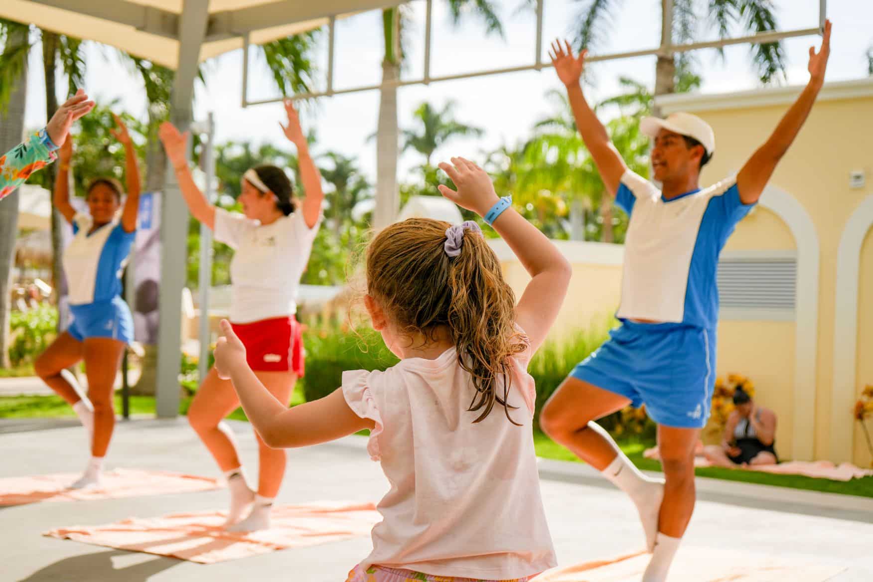 Niña imitando la postura del árbol en una clase de yoga infantil guiada por monitores en el Hotel RIU Guanacaste